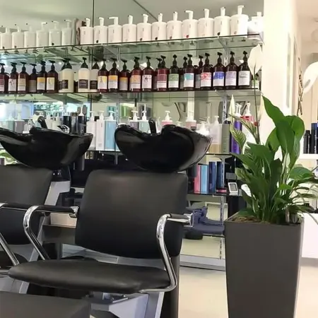 Moderner Friseursalon mit Waschbecken, Friseurstühlen, Pflanzen und Pflegeprodukten.