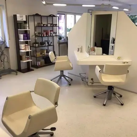 Moderner Friseursalon mit hellen Drehstühlen, Spiegeln und Regalen mit Haarpflegeprodukten.
