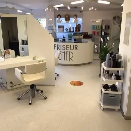 Moderner Friseursalon mit hellen Möbeln, Spiegel, Stylingprodukten und Empfangstresen.