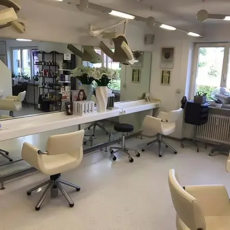Moderner Friseursalon mit hellen Drehstühlen, Spiegeln und Haarpflegeprodukten.